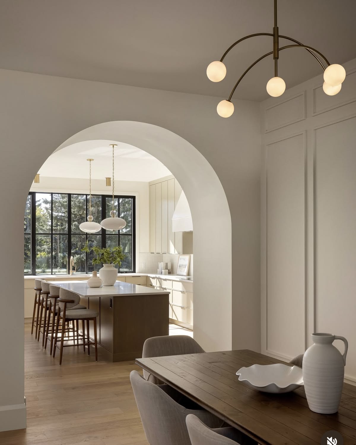 Arched opening between a dining room and a pale, contemporary kitchen
